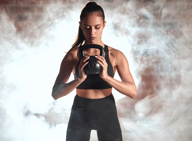 Young,Caucasian,Woman,Stand,Holding,Kettlebell,In,Two,Hands.,Steam