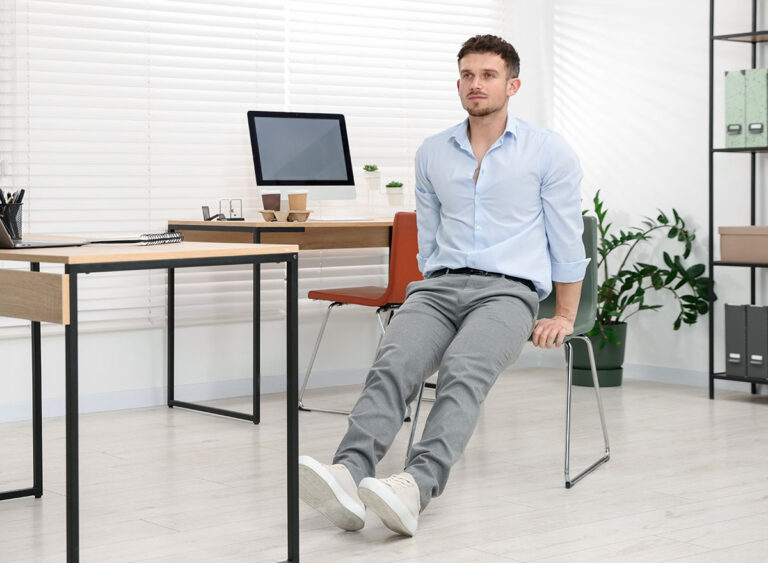 Handsome,Man,Exercising,With,Chair,In,Office