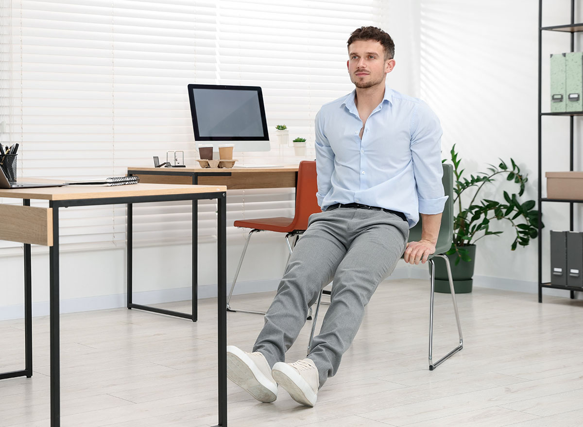 Handsome,Man,Exercising,With,Chair,In,Office