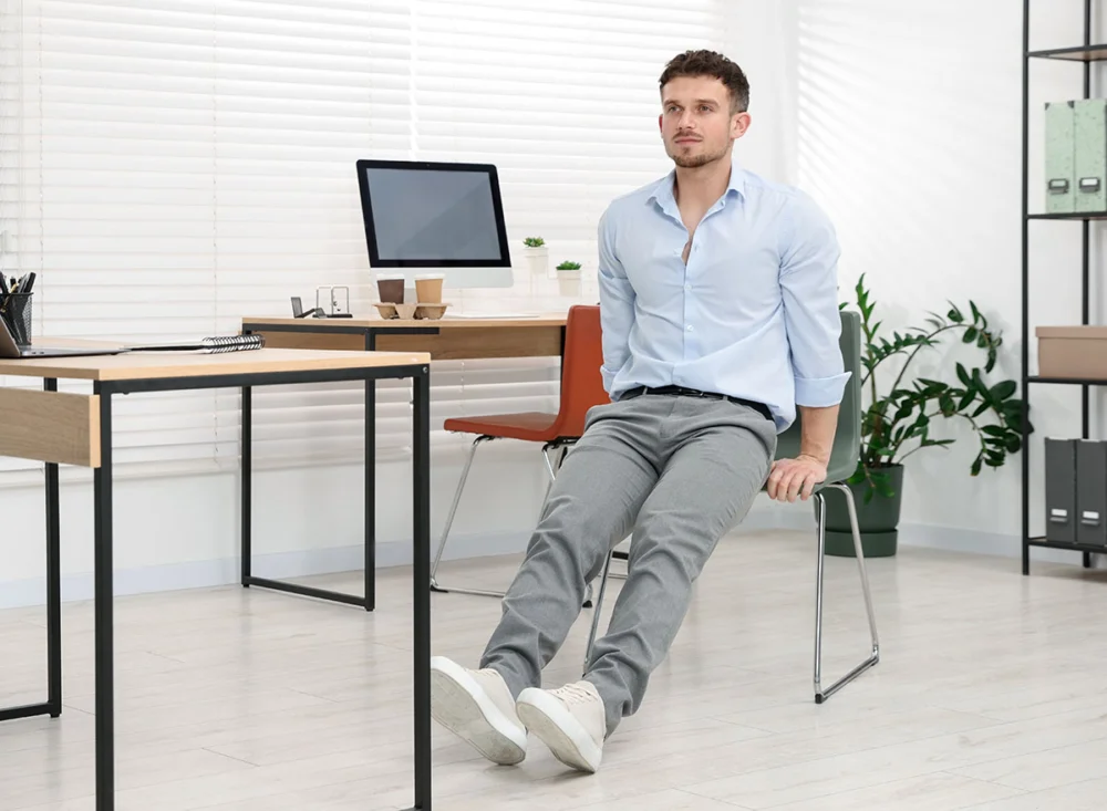 Handsome,Man,Exercising,With,Chair,In,Office