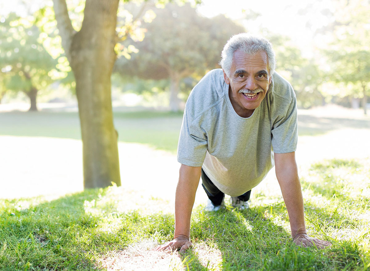 Senior,Man,Doing,Push-ups,By,Tree,Trunk,In,Park,Wearing