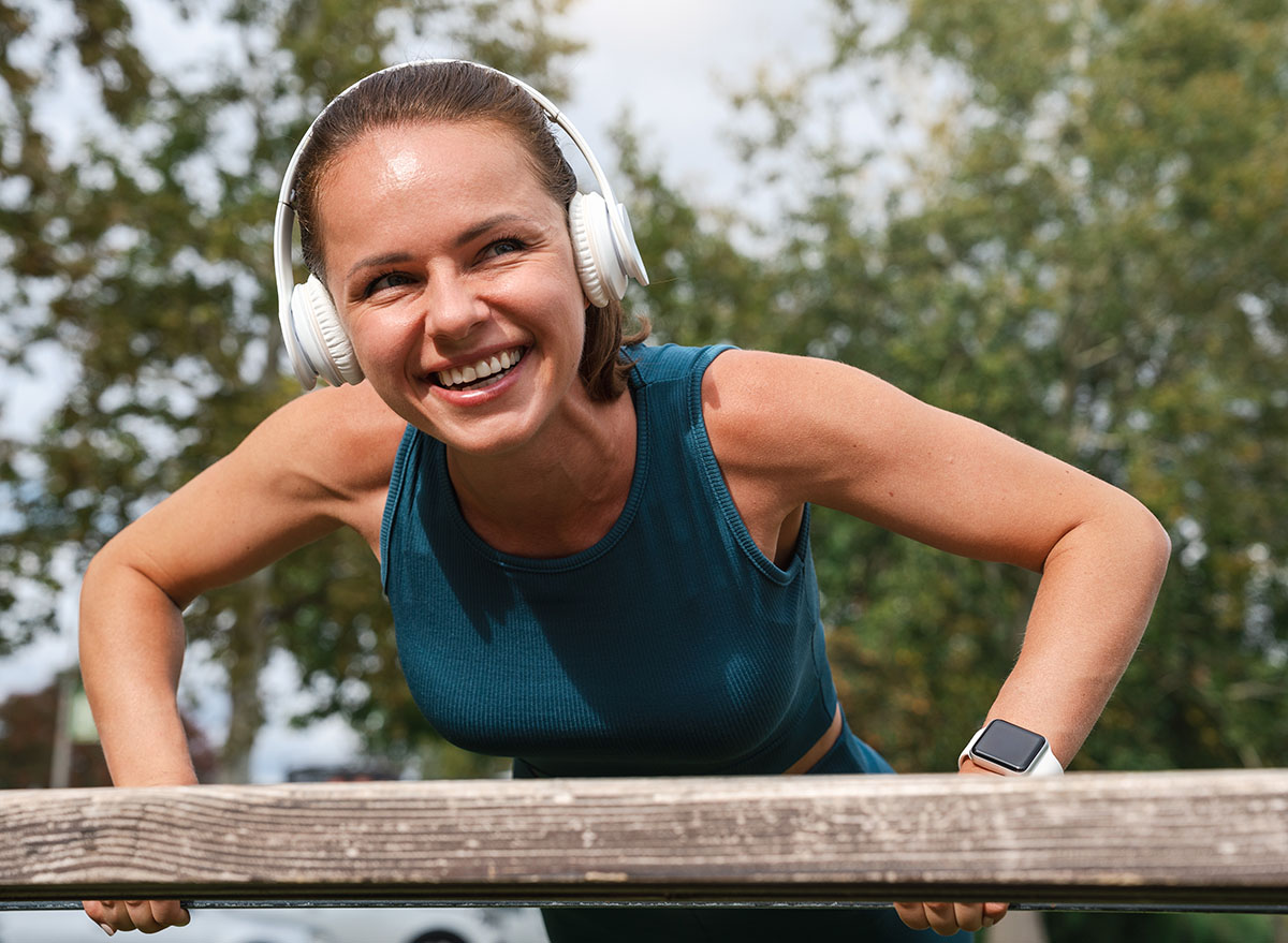 Young,Adult,Caucasian,Woman,In,Headphones,Performing,Push-ups,On,A