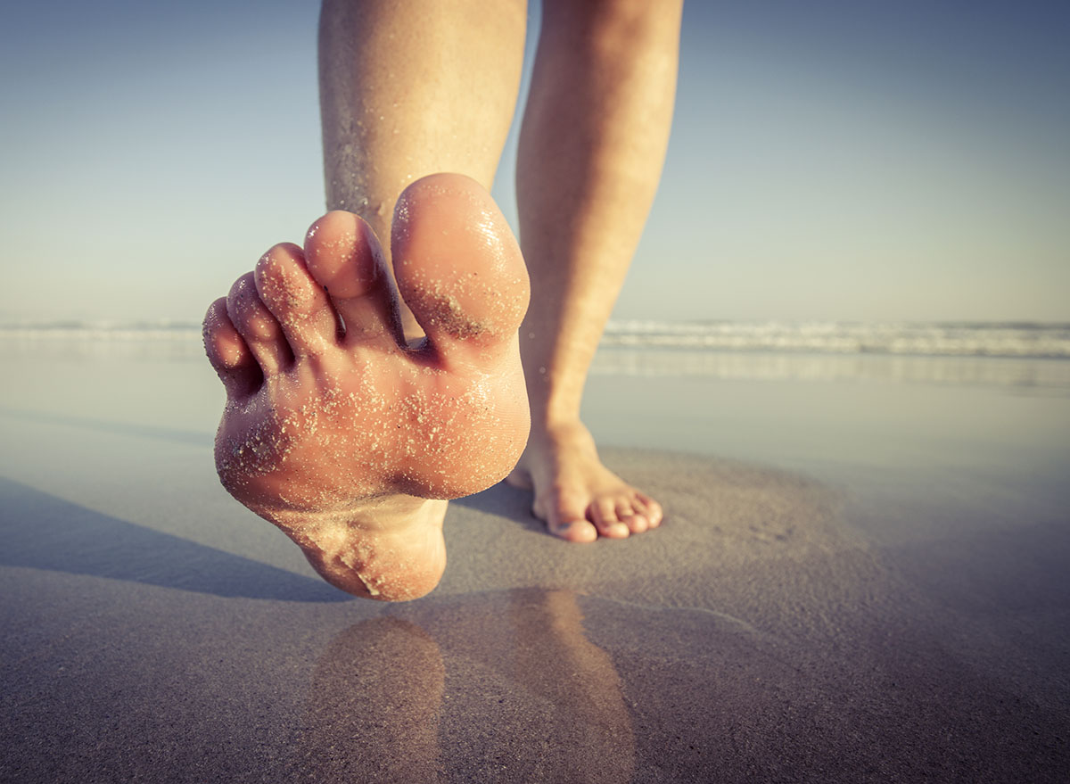 Close,Up,Of,A,Woman,Walking,On,Wet,Sand,On