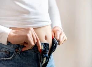 Woman,With,A,Bloated,Belly,Trying,To,Button,Up,Her
