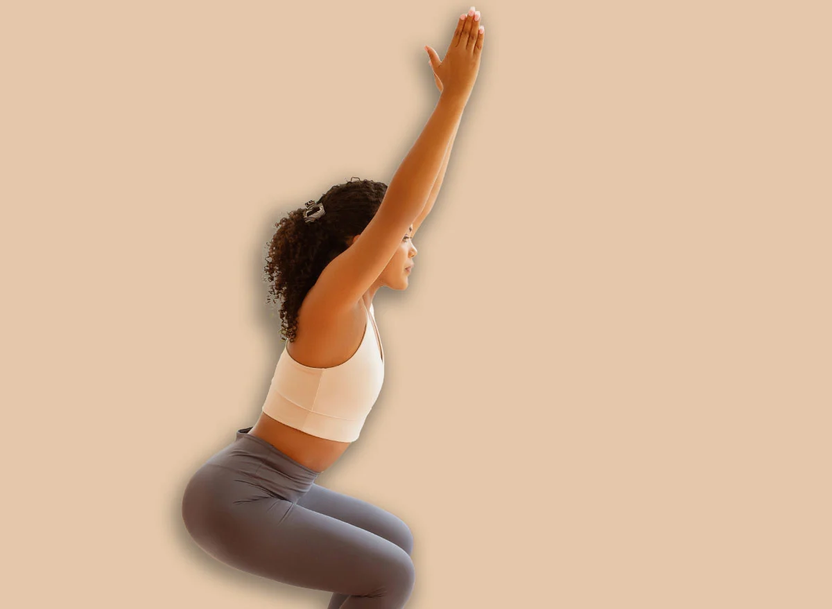 Young,Lady,Doing,Squats,With,Raised,Arms,Indoors,,Engages,In